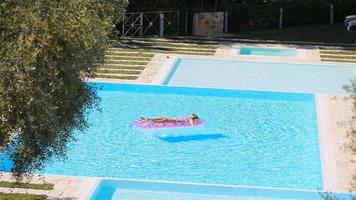 jovem em colchão de ar de biquíni na grande piscina video