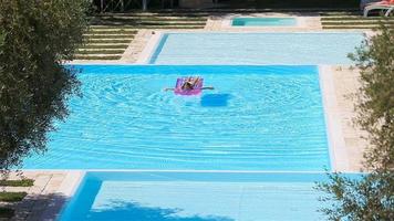adorable fille avec matelas gonflable dans la piscine extérieure video