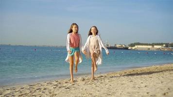 Little happy funny girls have a lot of fun at tropical beach playing together. Sunny day with rain in the sea video