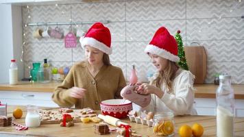 Kleine Mädchen machen Weihnachtslebkuchenhaus am Kamin im dekorierten Wohnzimmer. video