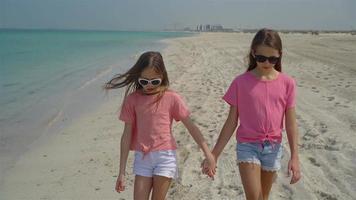 Little happy funny girls have a lot of fun at tropical beach playing together. video