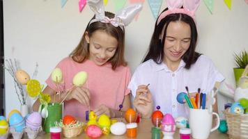 mãe e sua filha pintando ovos. família feliz se preparando para a páscoa. video