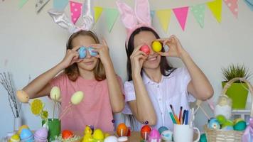 madre y su pequeña hija pintando huevos. familia feliz preparándose para pascua. video