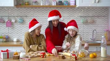 Happy family mother and daughters bake cookies for Christmas