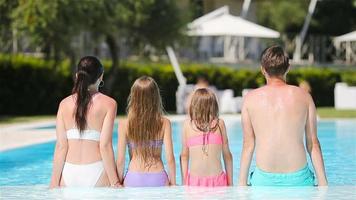 famille heureuse de quatre personnes dans une piscine extérieure video