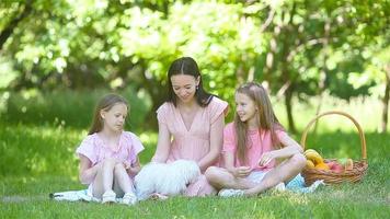 la madre feliz y las hijas pequeñas se relajan junto al lago video