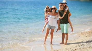 joven familia en vacaciones caminando por el mar video