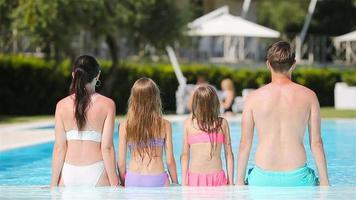 famille heureuse de quatre personnes dans une piscine extérieure video