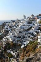 Charming view Oia village on Santorini island, Greece. Traditional famous blue dome church over the Caldera in Aegean sea. Traditional blue and white Cyclades architecture. photo