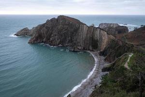 silencio playa, arena plateada ensenada Respaldados por un natural rock anfiteatro en Asturias, España. foto