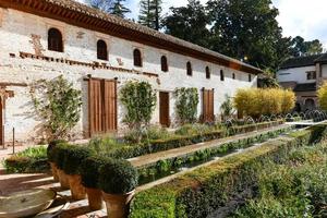 View of The Generalife courtyard, with its famous fountain and garden through an arch. Alhambra de Granada complex at Granada, Spain, Europe on a bright winter day. photo