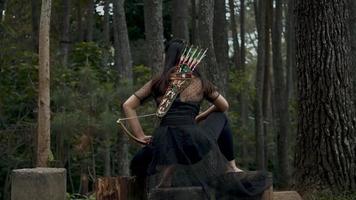 Asian Women sitting on a piece of tree and holding a bow on her hand video