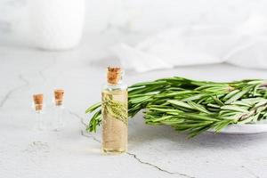 un botella de Romero esencial petróleo y hierba ramas en un plato en el mesa. orgánico aromático natural recurso. foto