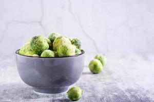 congelado Bruselas coles en un cuenco en un gris antecedentes. vegetariano alimento. foto