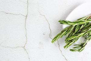 Sprigs of fresh rosemary on a plate on the table. Organic aromatic herb for cooking and health. Top view. Copy space photo