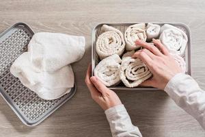 Women's hands neatly fold towels in a clothes drawer. Organization and order at home. Top view photo