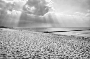 Sun rays shining through dense clouds on the beach of the Baltic Sea. black and white photo
