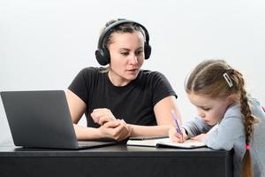 a young woman in headphones works on a laptop and exercises with her daughter at the same time. photo