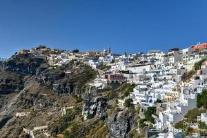 Charming view Fira village on Santorini island, Greece. Traditional famous blue dome church over the Caldera in Aegean sea. Traditional blue and white Cyclades architecture. photo