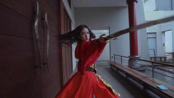 una mujer china agitando una espada plateada mientras usa un vestido chino rojo video