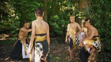 A man with a golden costume and golden crown talks to a group of a man near the green tree video