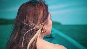 An Asian woman with blonde hair is enjoying the sea breeze while boarding a fishing boat while on vacation and is very relaxed video