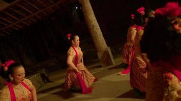 Javaner tanzen zusammen in einem orangefarbenen Kleid mit einem grünen Schal, während das Fest im Dorf beginnt