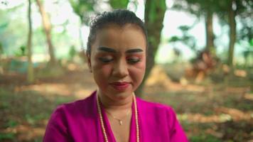une Javanais femme avec une rose robe souriant avec bonheur tandis que portant or bijoux sur sa cou à l'intérieur le village video