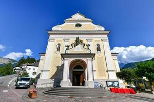 Yellow and orange Neoclassical style facade of Catholic Parish Church of St. Ulrich in Ortisei in Dolomites Alps in Italy photo