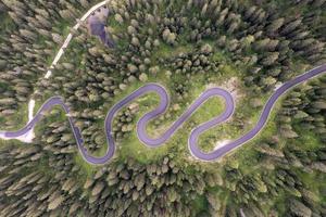 Top aerial view of famous Snake road near Passo Giau in Dolomite Alps. Winding mountains road in lush forest with green spruce in summer time in the Dolomites, Italy photo