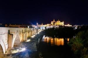 View of the Roman Bridge, a stone bridge that spans the river Guadalquivir in Cordoba, Spain at night. photo