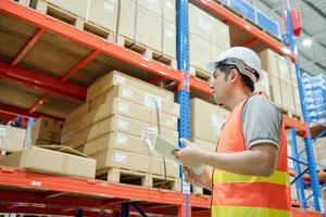 asian man business owner using checklist recheck amount of stock product inventory on shelf at distribution warehouse factory.logistic business ship and delivery, inventory flow, professional. photo