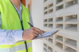 el inspector o ingeniero está inspeccionando la construcción y el aseguramiento de la calidad de la nueva casa usando una lista de verificación. ingenieros o arquitectos o contratistas trabajan para construir la casa antes de entregársela al propietario foto