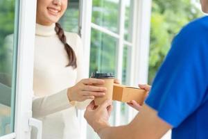 una mujer feliz y sonriente recibe un paquete de cajas del servicio de mensajería en la casa principal. repartidor enviar entregar express. compras en línea, contenedores de papel, comida para llevar, cartero, servicio de entrega, paquetes foto