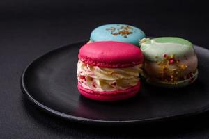 Beautiful tasty macaron with filling and fruit flavor on a black plate photo