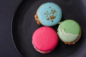 hermosa sabroso macaron con relleno y Fruta sabor en un negro plato foto