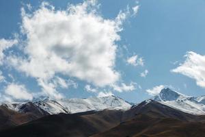 blanco nube terminado el montañas. azul cielo y Nevado montañas. foto