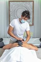 Rear view of an adult woman having hot stone massage in spa salon while getting a head massage photo