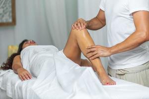 Therapist doing a leg massage to woman in spa salon photo