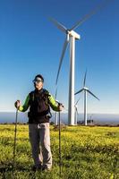 Hiker standing in blooming filed with windmills photo