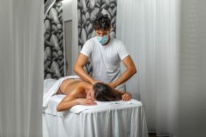 Male masseur giving a shoulder and back massage to calm woman in spa center photo