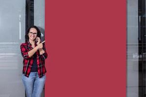 mujer hablando con el móvil mientras señalando a un bandera en un ventana tienda foto