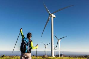 Traveling man with raised hand in field with windmills photo