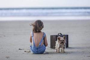 Yorkshire terrier cerca niña en playa foto