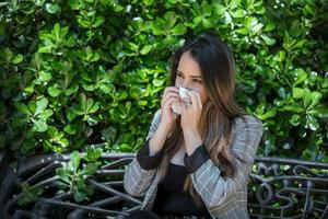 Woman with hay fever sneezing into tissue photo
