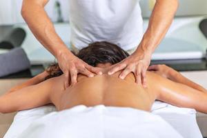 Rear view of relaxing woman lying face down on massage table receiving a back massage photo