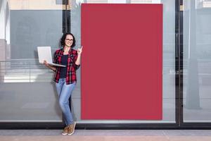 foto con Copiar espacio de un vendedora con un ordenador portátil mientras señalando un rojo bandera