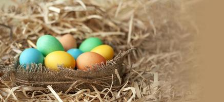 Easter eggs of different colors in a nest made of burlap. Happy Easter. Close-up banner. photo
