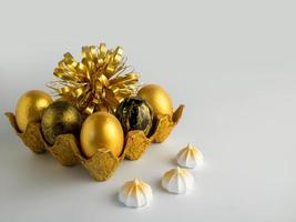 Easter eggs painted in gold and black in a textured stand on a white background with meringues photo