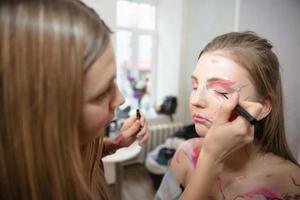 The artist applies makeup to a beautiful young model photo